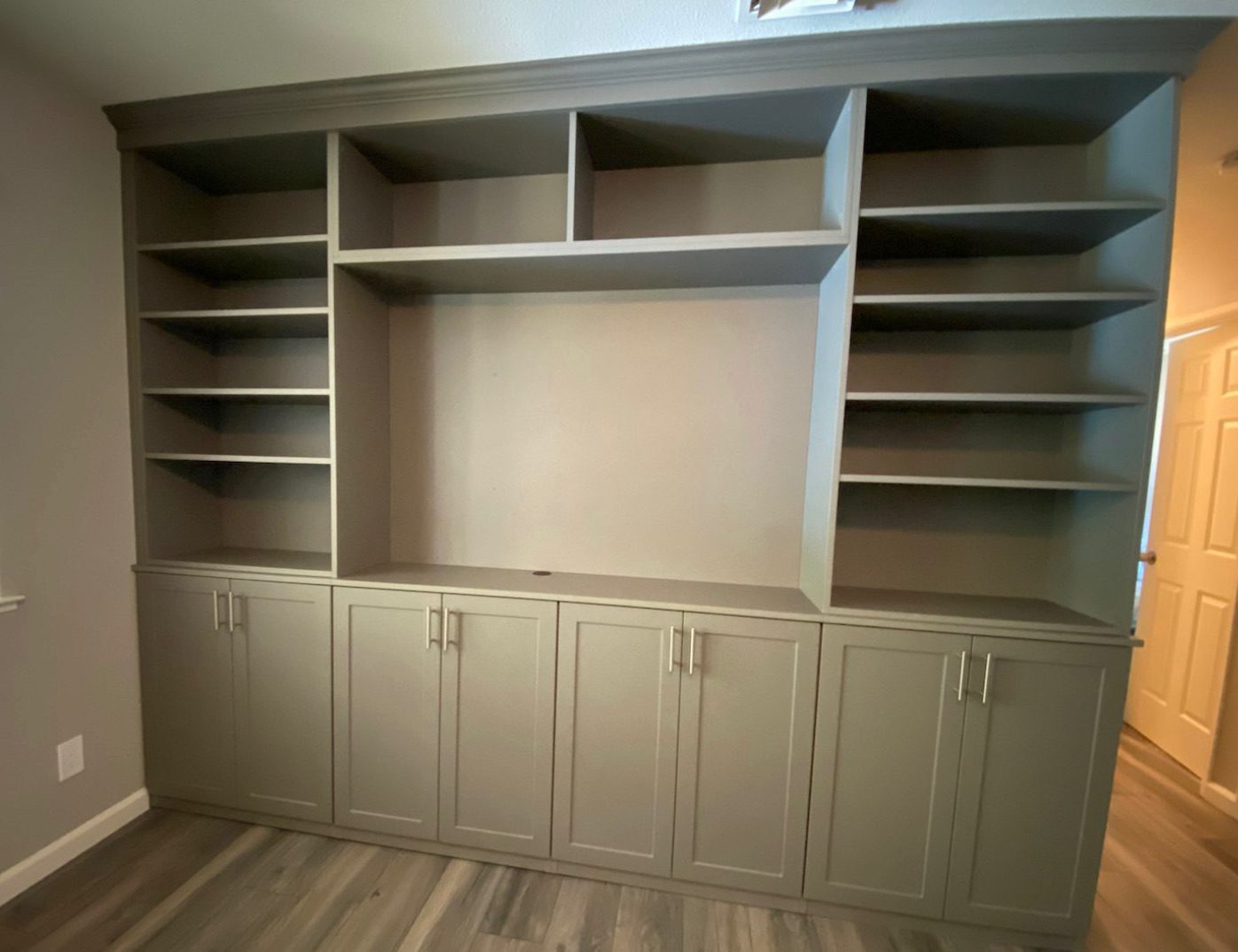 Gray built-in bookcase wall with adjustable shelves over shaker-style base cabinets