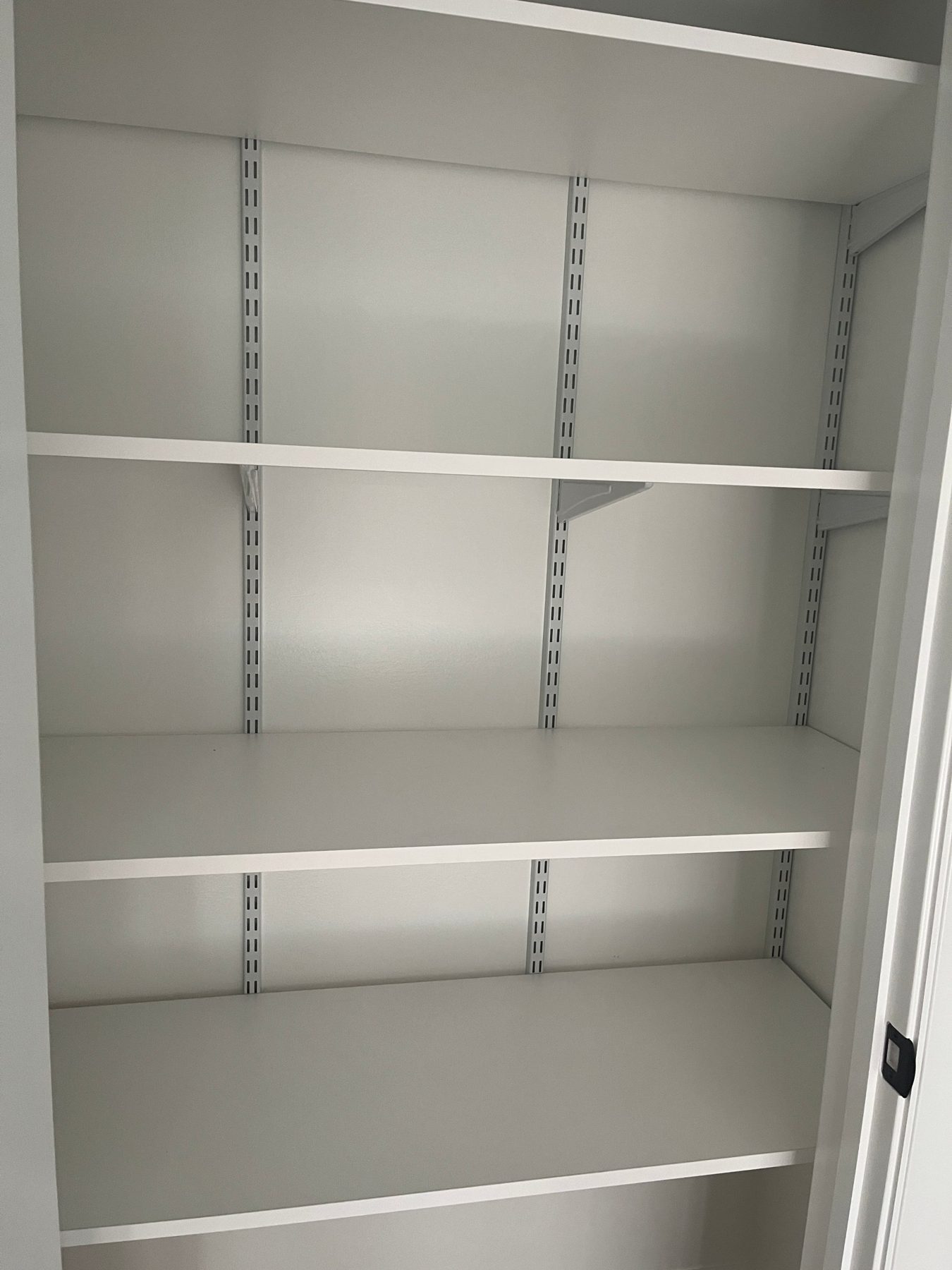 Reach-in pantry closet with deep white shelves on adjustable wall standards